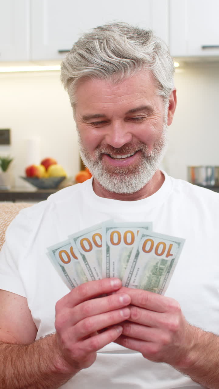 Medelålders man räknar pengar, kontanter, dollar, ler åt planer, inköp, lön, bonus, sparande, investering