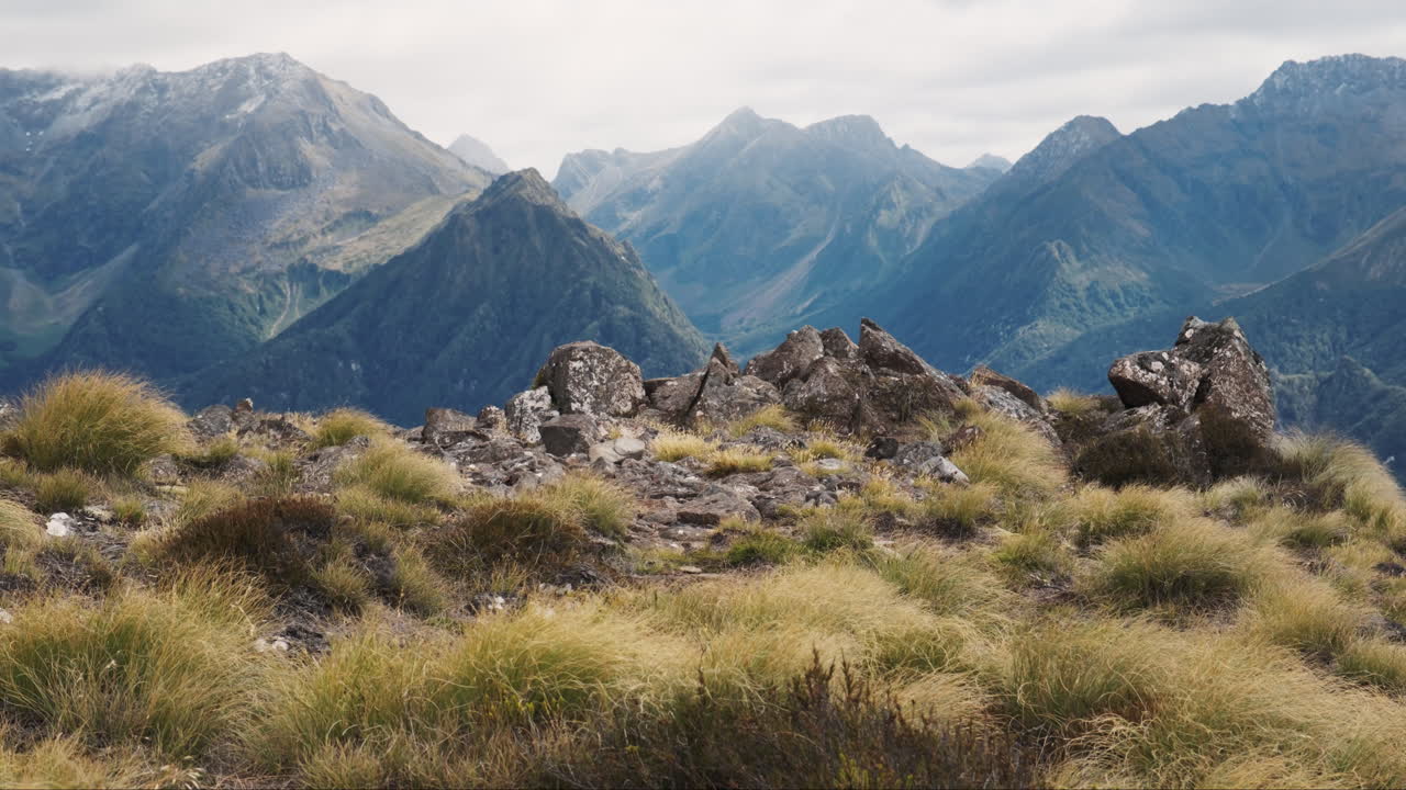 Episk newzealandsk barskt bjerglandskab med spidse klipper i forgrunden.
