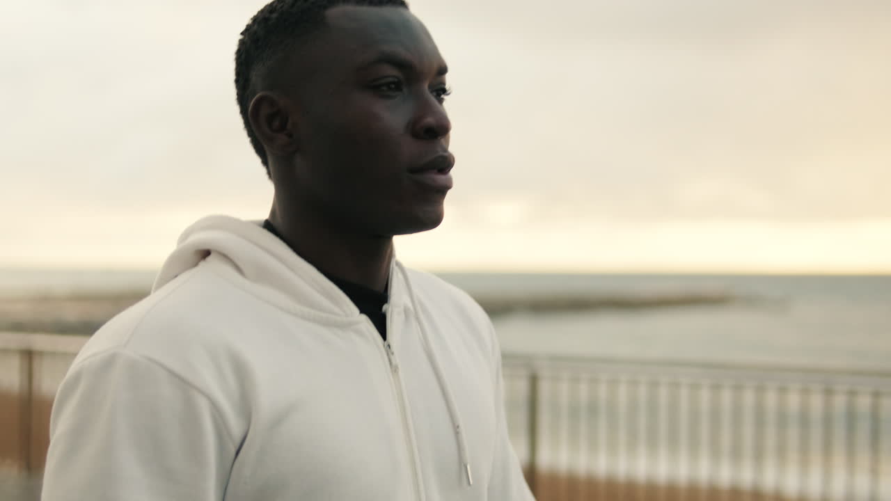 Thoughtful Young Black Man Standing by the Ocean at Dawn