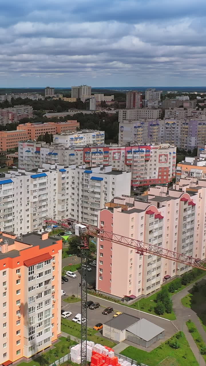 New architecture in the city. Luxury design of apartment building in a sunny day. Orange and white high-rise apartment with balconies. View from the drone Vertical video