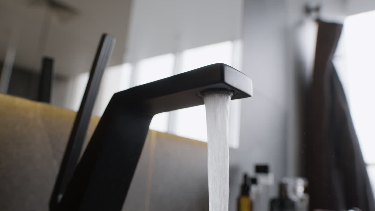 Close-up of a modern black faucet with water flowing
