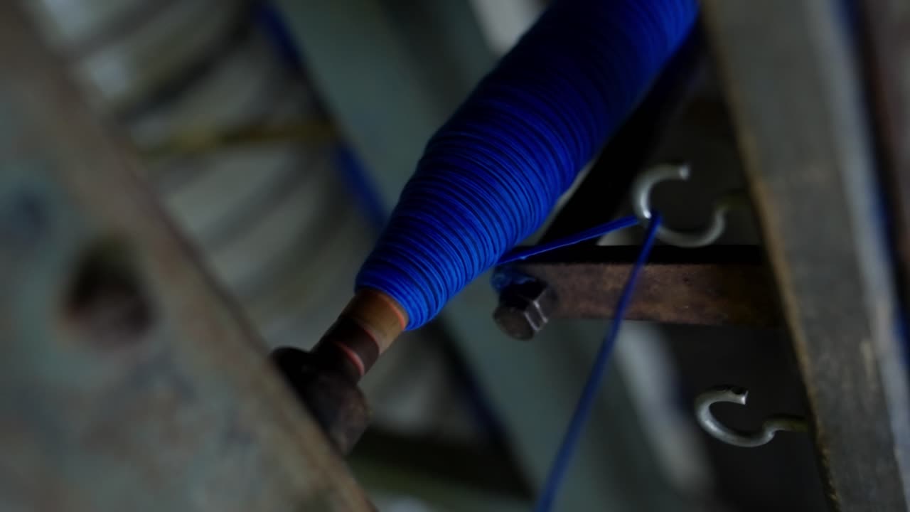 Detailed close-up of blue wool yarn bobbin spinning on machinery in a textile mill