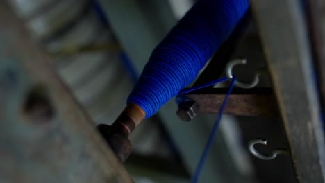 detailed close-up of blue wool yarn bobbin spinning on machinery in a textile mill