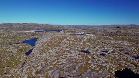 Aerial-pan-across-the-rocky,-mossy-landscape-of-Rogaland,-Norway