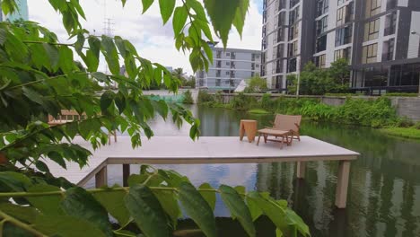 wooden pier with seating at a coffee shop in the city of bangkok with a lake surrounded by apartment buildings