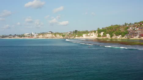 The surf spot of Bingin at the cliffs of Uluwatu during a sunny day. Aerial shot.