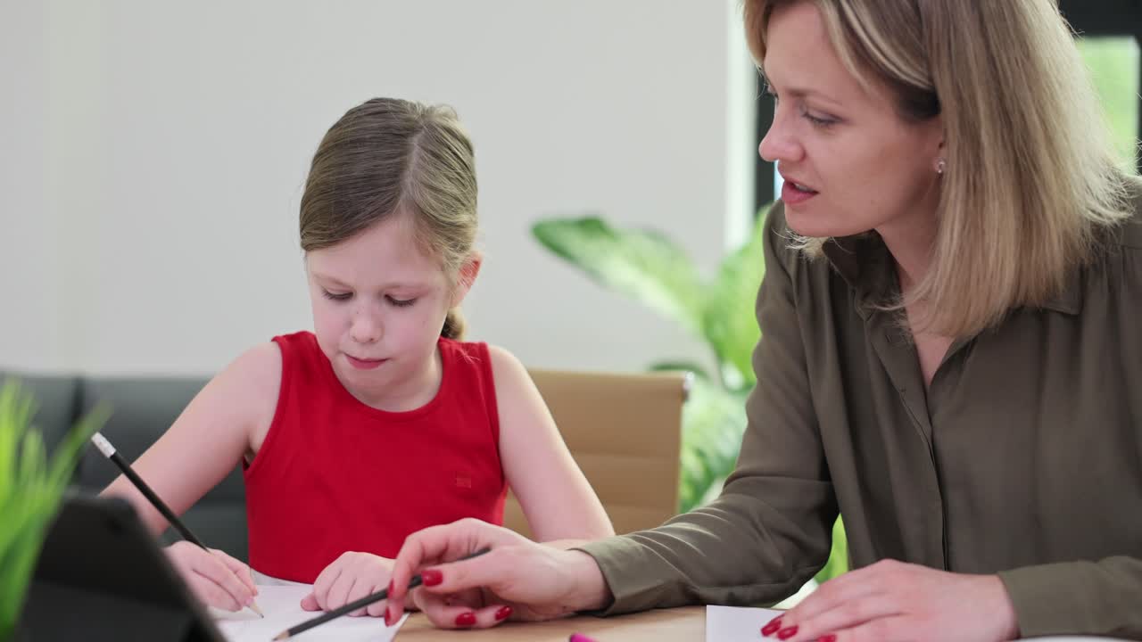 Mother helping her daughter with drawing