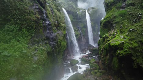 a breathtaking view of a man in the quebrada gata waterfalls in costa rica, showcasing multiple powerful cascades plunging into a rocky riverbed