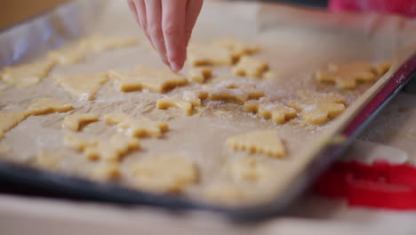 close-up of boy's hand who sprinkles sugar on fresh cookies