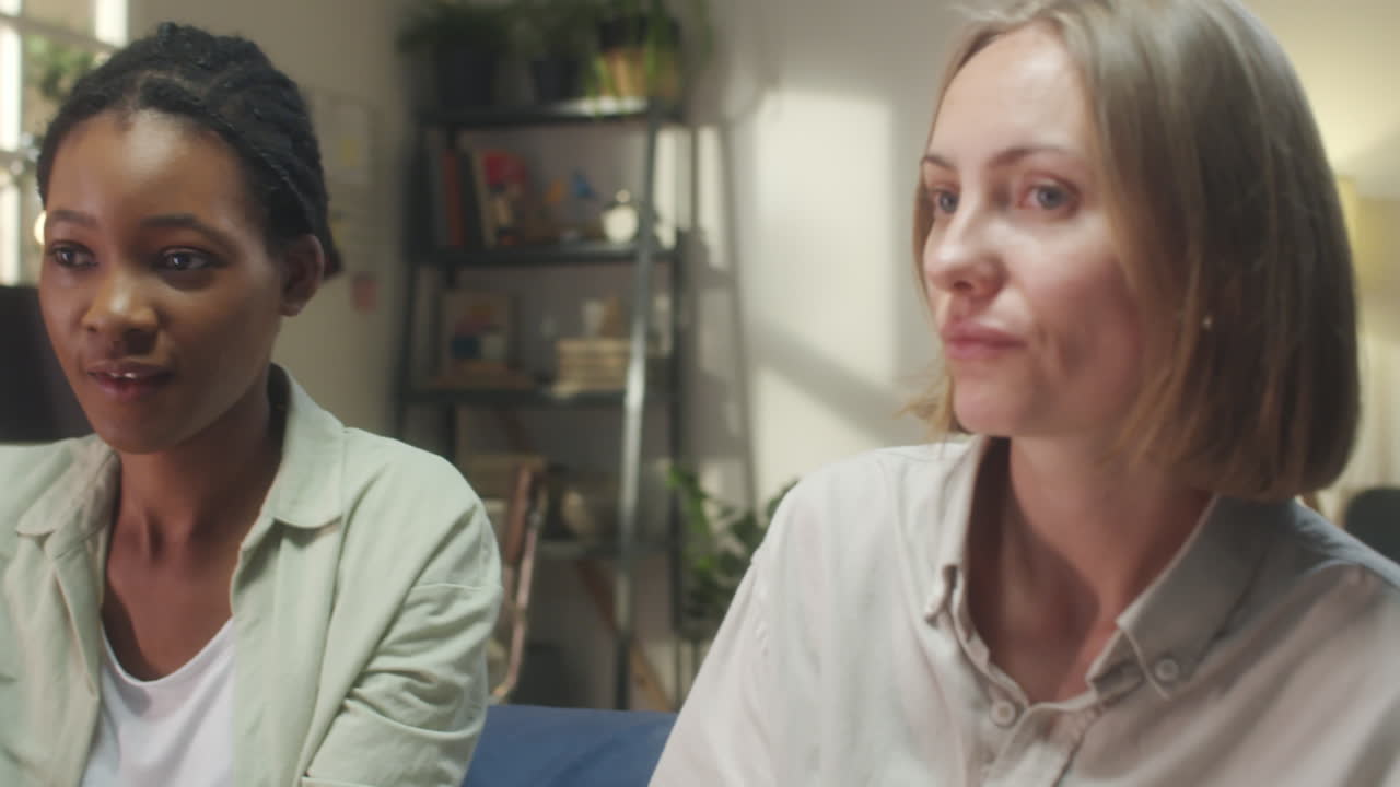 Two Diverse Women Having a Conversation and Sharing a Smile Indoors