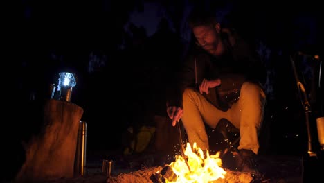 man sitting near campfire in the forest 4k