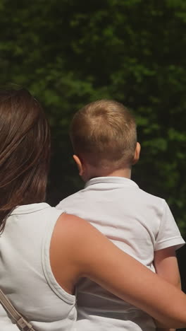 una mujer con un niño pequeño descansa junto a la cascada del río en las vacaciones de verano