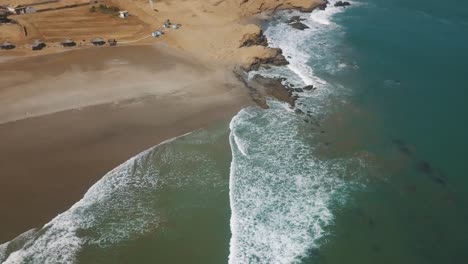 Vista-Aérea-De-Surfistas-Flotando-En-La-Superficie-Del-Océano-Cerca-De-La-Costa-En-Lobitos,-Perú-Durante-El-Verano