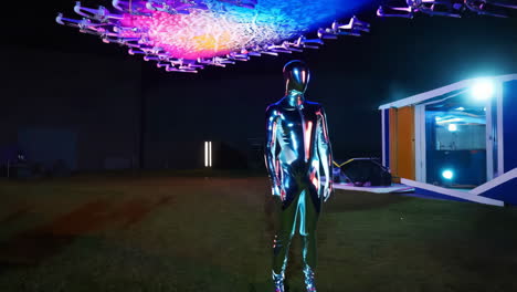 a metallic figure stands under a futuristic drone light show