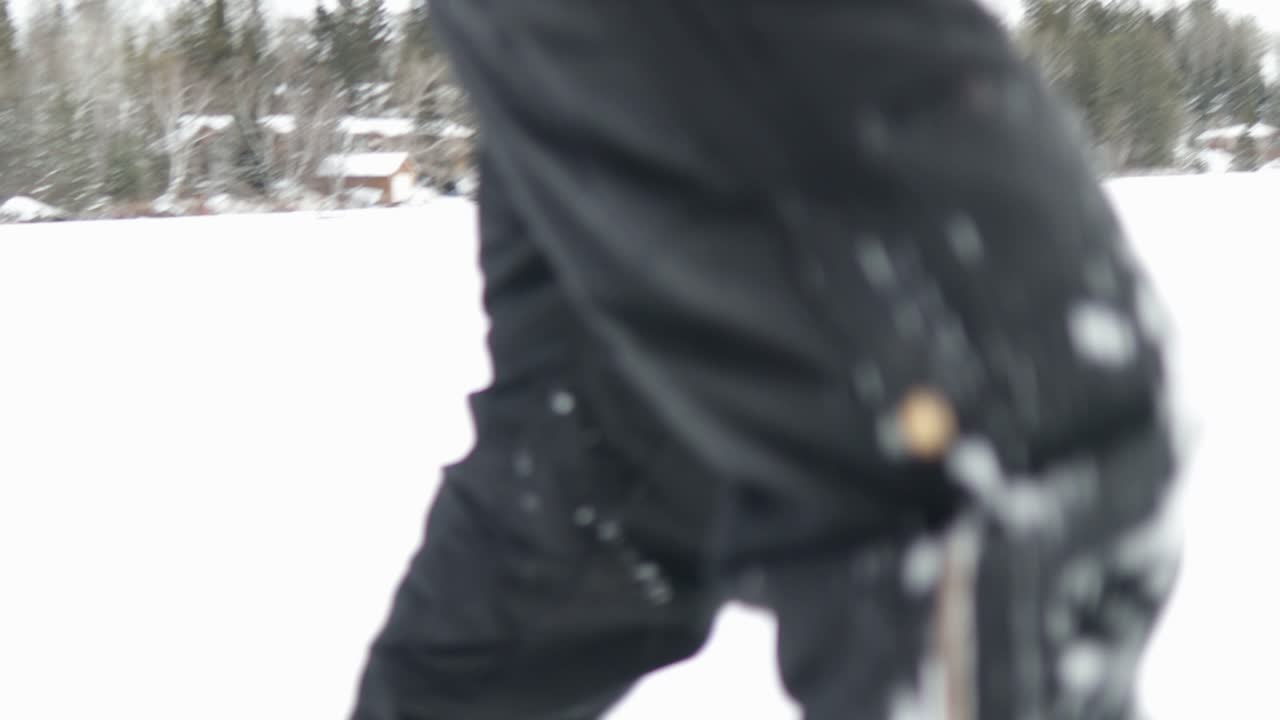 Cinematic rough jerky camera action of a man walking in and out of focus in snow shoes in the Canadian arctic