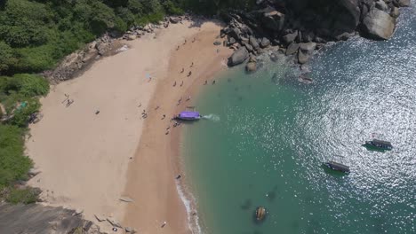 a stunning aerial top view of butterfly beach in goa, india, showcasing its pristine golden sands, waters and lush green surroundings. a boat floats near the shore, with people enjoying the sunny day