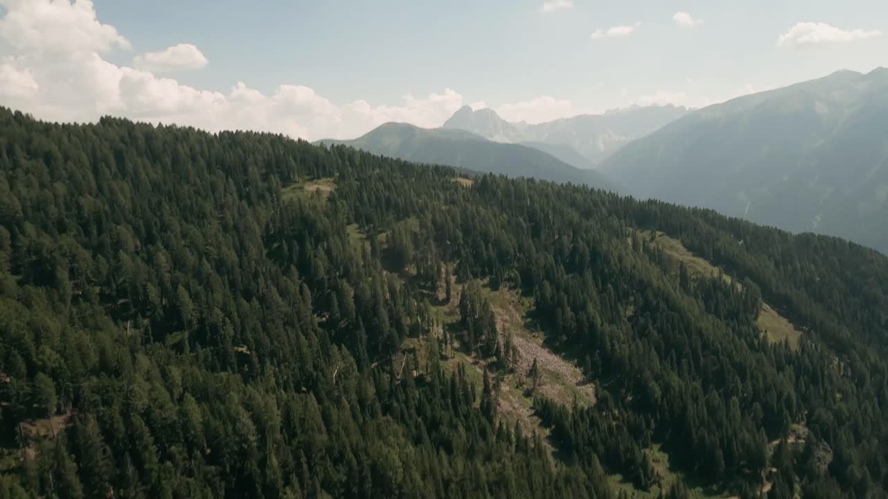volar a través de un paisaje boscoso, revelando una vista impresionante de las montañas dolomitas en este cautivador fpv drone imágenes por encima de la aldea de luzen