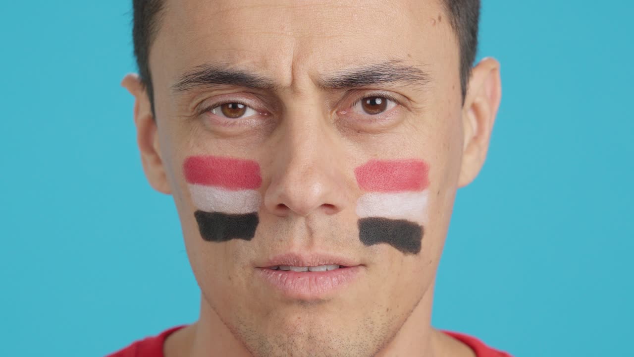 Man with a egyptian flag painted on the face smiling