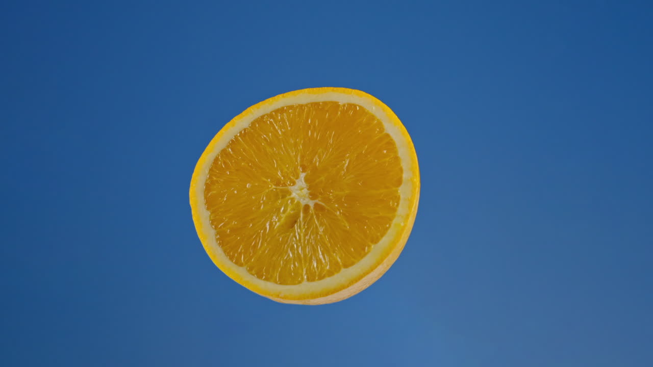 Nahaufnahme einer saftigen Orangenhälfte vor blauem Hintergrund, Loop-fähiger Chroma Key.