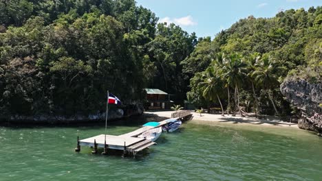 pequeño embarcadero de madera con bandera dominicana en la exótica y tropical playa de la bahía de san lorenzo, parque nacional los haitises en república dominicana