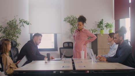 pregnant woman explaining a project in front of her coworkers in a meeting room 8