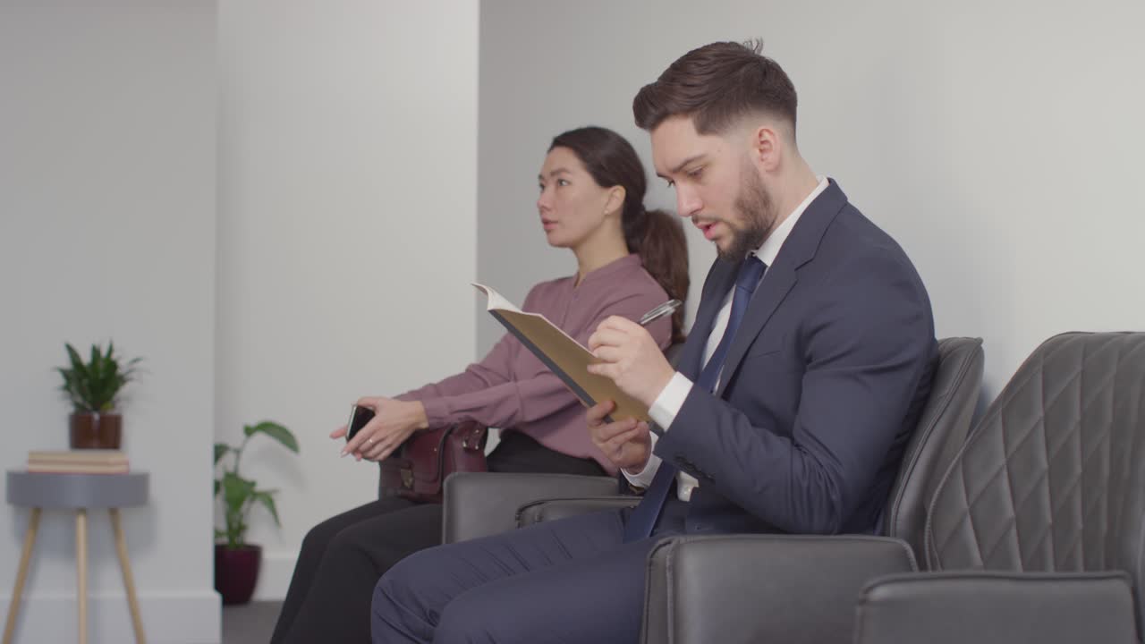 candidatos masculinos y femeninos en el cargo esperando una entrevista de trabajo mirando el teléfono móvil y leyendo notas 3