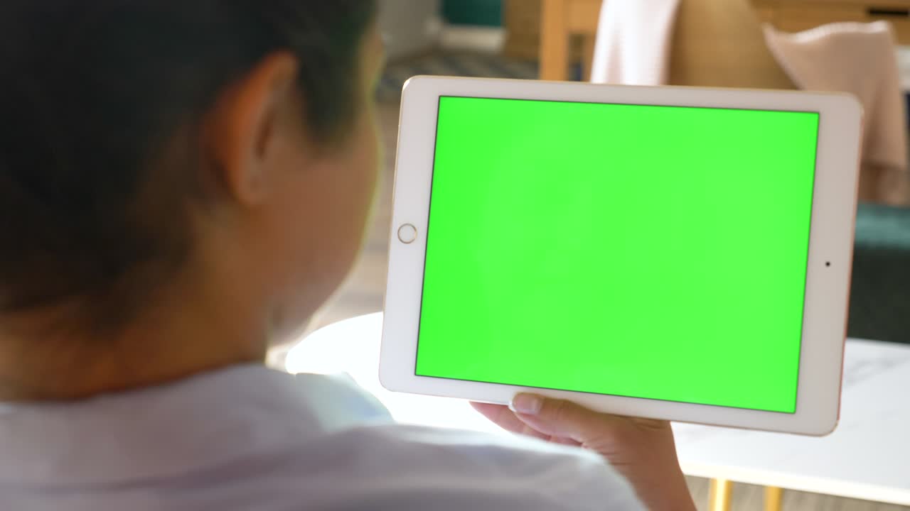 젊은 인디언 매력적인 여성이 카페에서 녹색 화면으로 태블릿에서 비디오를보고 있습니다. 클로즈업. 크로마 키.