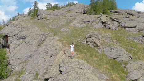drone vuela sobre montañas impresionantes con una chica caminando en un acantilado