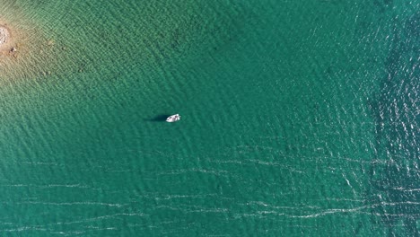 aerial drone shot of a boat drifting in clear turquoise water near the shoreline in a tropical setting
