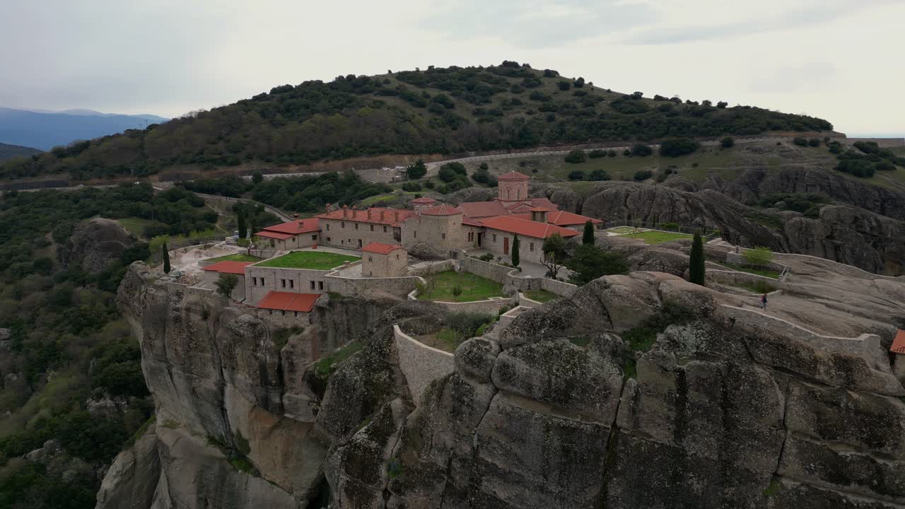 Aerial flyover of Meteora monastery with dramatic cliffs and expansive valley below
