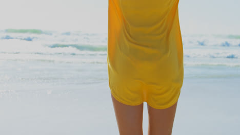 rear view of young caucasian woman standing with arms outstretched on the beach 4k