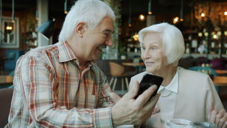 older couple using smartphone in cafe