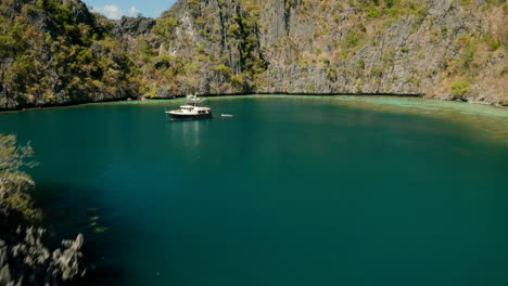 aerial shot flies low over outrigger boats on matinloc island, el nido, palawan, phillipines.