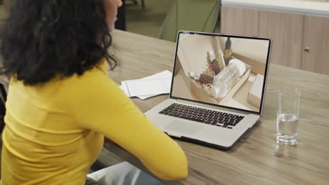 biracial woman at table using laptop, online shopping for beauty products, slow motion