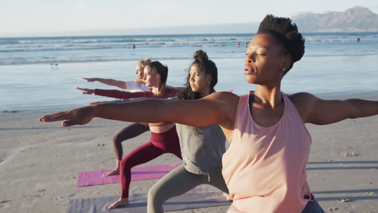 Group of diverse female friends practicing yoga at the beach