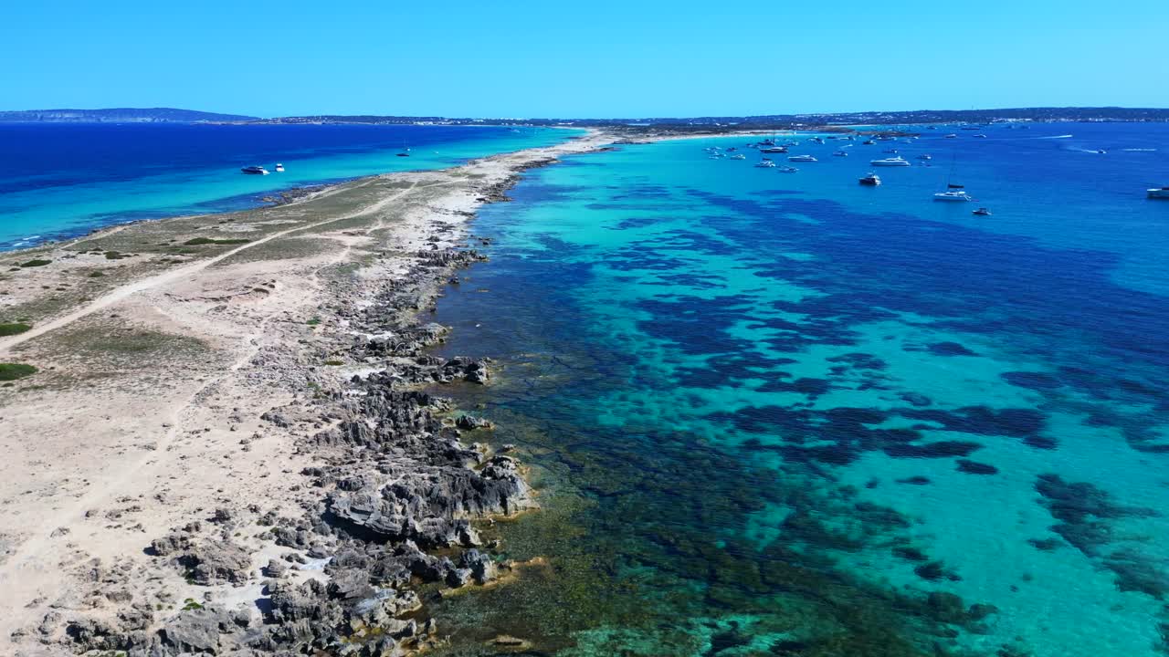Punta des Borronar beach on Formentera Ibiza island with yachts mooring in clear turquoise water. Unique aerial view flight fly reverse drone