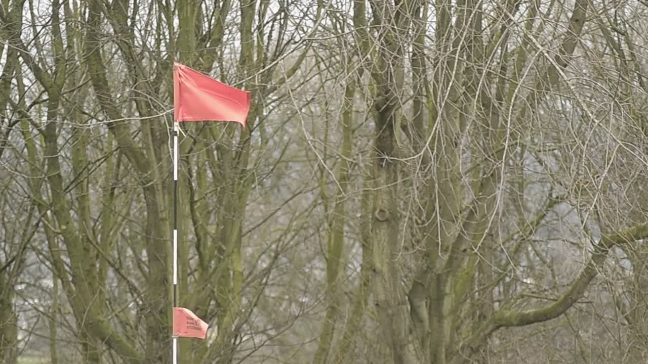 Czerwona flaga golfowa łopocze na wiejskim polu golfowym