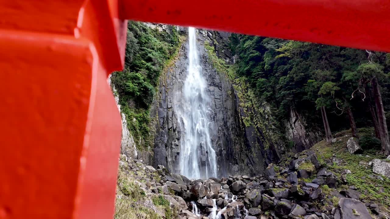 Low angle view of Nachi Falls, framed by a traditional red japanese shrine gate in Nachikatsuura, Japan. Slow Dolly Right