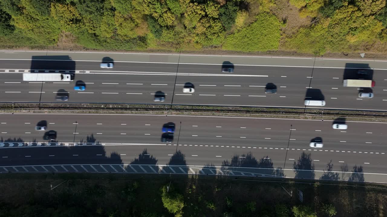 Aerial drone top down video of busy M1 motorway highway near Leicester, England, UK, at sunset with traffic vehicles driving by and dramatic long shadows