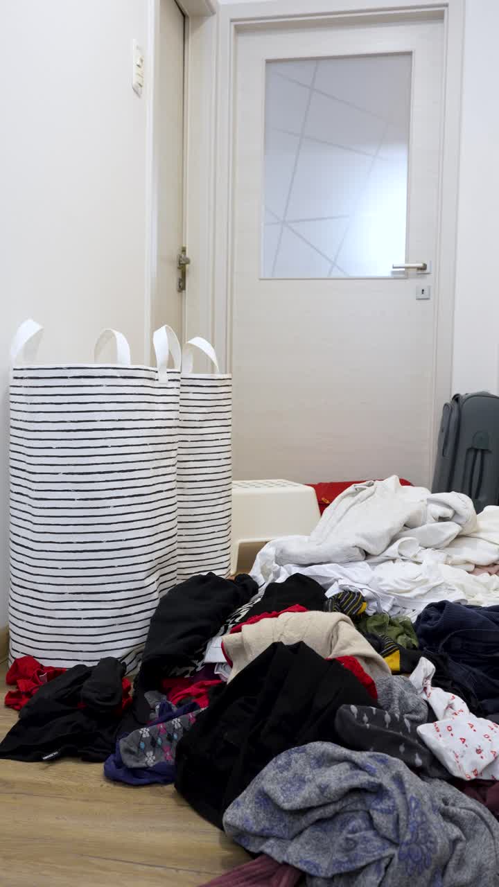 Home interior messy pile of dirty clothes on floor vertical shot, busy laundry day household chores indoors
