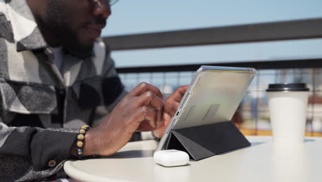 man using tablet in outdoor cafe