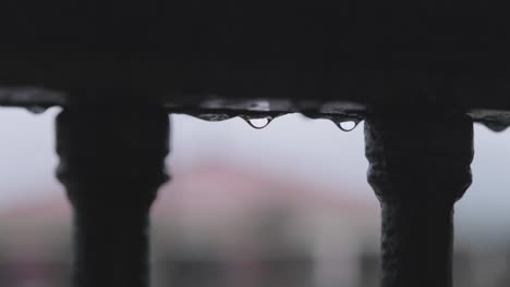 close-up of iron railing with raindrops after rain in hondarribia, spain, with blurred rooftops in the background