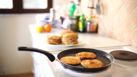 close-up of three golden ruddy pancakes in a frying pan, light white steam.