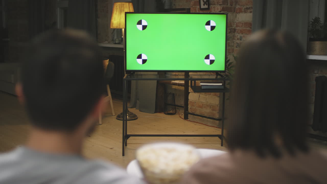 Couple Eating Popcorn While Watching Football On TV