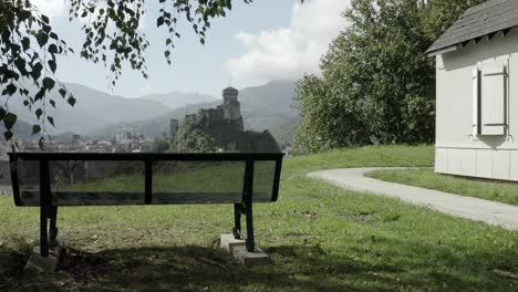 Panorama-Bank-Auf-Der-Wiese-Mit-Schloss-Fort-De-Lourdes-Im-Hintergrund,-Hautes-Pyrenäen-In-Frankreich