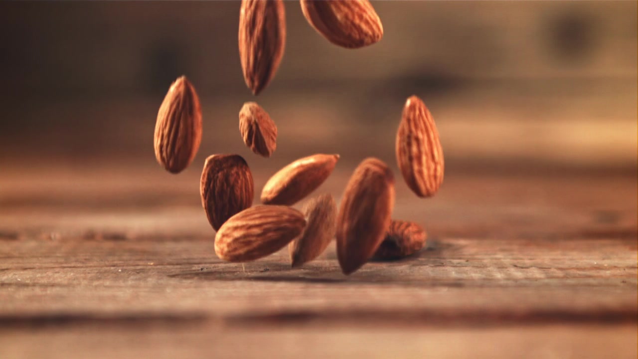 Amandes tombant au ralenti sur une table en bois.