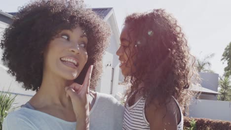 happy african american mother and daughter embracing and kissing in garden, slow motion