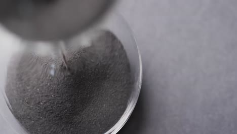 video of close up of hourglass with sand pouring, copy space on grey background