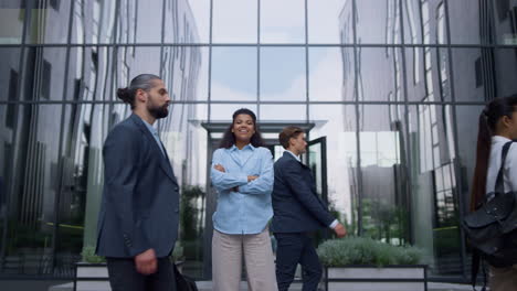 satisfied corporate manager smiling crossing hands people flow on office street.