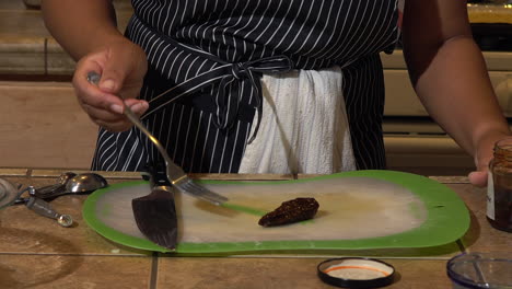 Cutting-a-piece-of-jarred-chili-on-a-green-plastic-chopping-board---Close-up